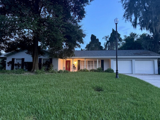 ranch-style home featuring a garage and a front lawn