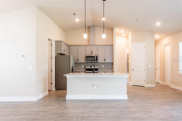 kitchen with gray cabinetry, hanging light fixtures, a kitchen island with sink, and stainless steel appliances