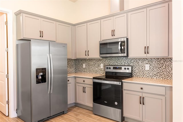 kitchen featuring stainless steel appliances, gray cabinets, light hardwood / wood-style flooring, and tasteful backsplash