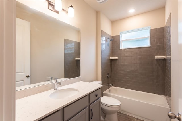 full bathroom featuring vanity, tiled shower / bath combo, and toilet