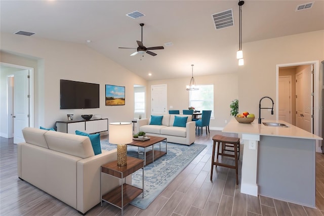 living room with lofted ceiling, sink, ceiling fan with notable chandelier, and light hardwood / wood-style flooring