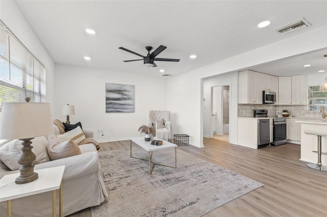 living room featuring ceiling fan, light hardwood / wood-style floors, and plenty of natural light