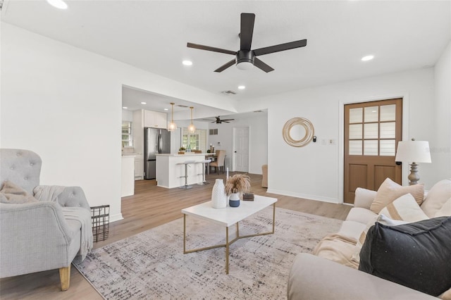 living room featuring light hardwood / wood-style floors and ceiling fan