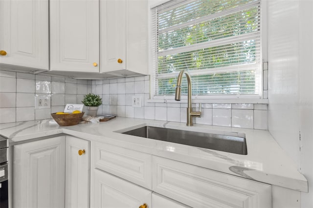 kitchen with white cabinetry, a wealth of natural light, sink, and tasteful backsplash