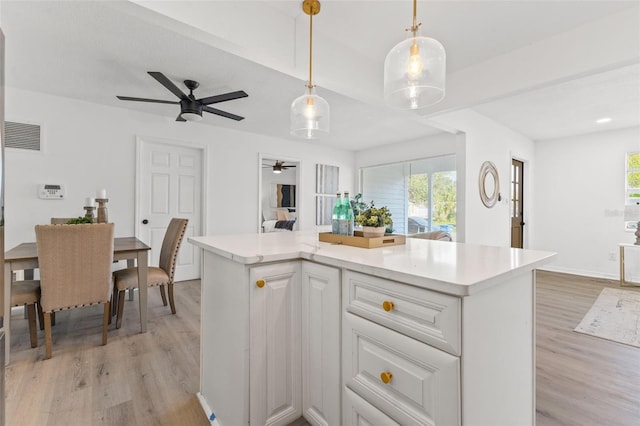 kitchen featuring a center island, hanging light fixtures, ceiling fan, white cabinetry, and light hardwood / wood-style flooring