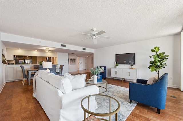 living room with ceiling fan, light hardwood / wood-style floors, and a textured ceiling