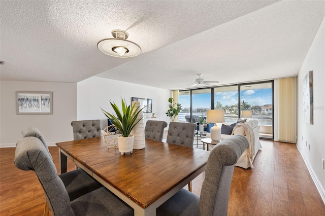 dining area with hardwood / wood-style floors, ceiling fan, expansive windows, and a textured ceiling