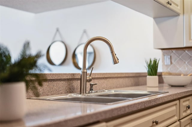 details featuring cream cabinets, sink, and backsplash