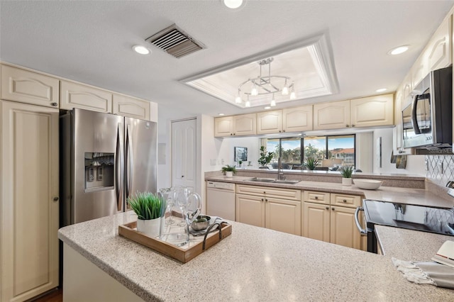 kitchen with sink, hanging light fixtures, stainless steel appliances, a raised ceiling, and a textured ceiling