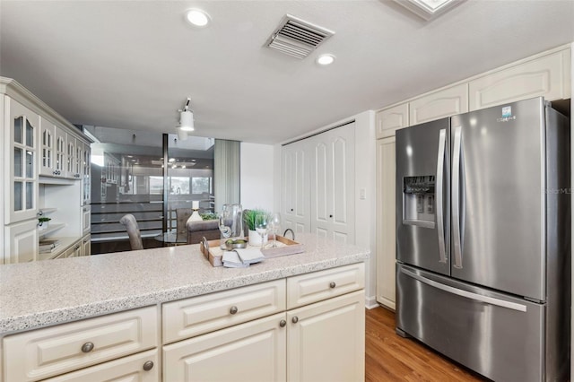 kitchen featuring light stone countertops, stainless steel refrigerator with ice dispenser, and light hardwood / wood-style flooring