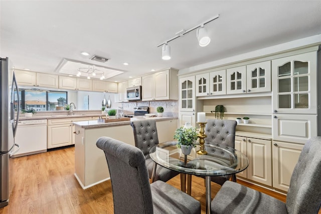 dining room with light wood-type flooring, track lighting, and sink