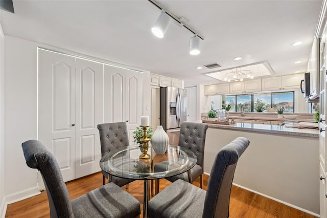 dining space with rail lighting, sink, and light wood-type flooring