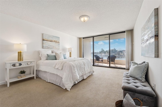 bedroom featuring a textured ceiling, access to outside, a wall of windows, and carpet floors