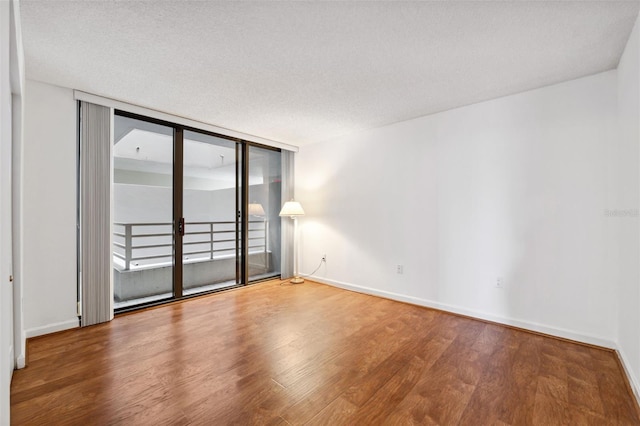 empty room with hardwood / wood-style floors, expansive windows, and a textured ceiling