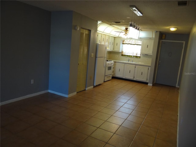 kitchen with pendant lighting, white appliances, sink, light tile patterned floors, and white cabinetry