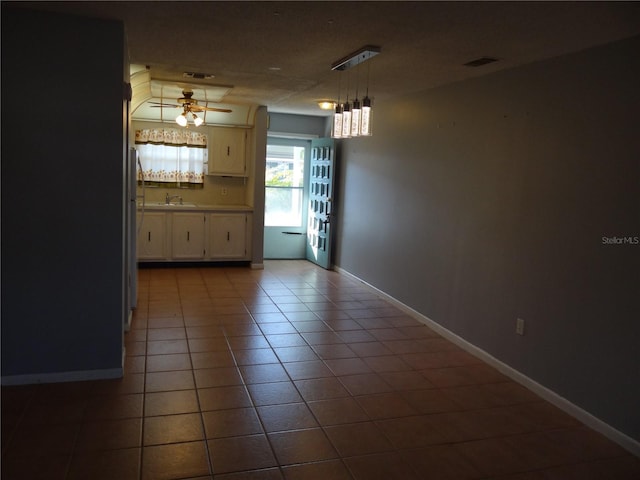 unfurnished dining area with tile patterned floors, ceiling fan, and sink