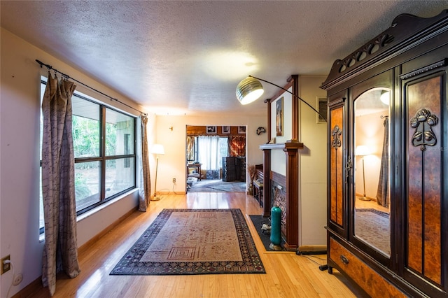 corridor with a textured ceiling and light hardwood / wood-style flooring