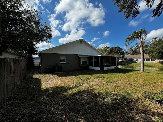 back of house with central AC unit, a sunroom, and a yard