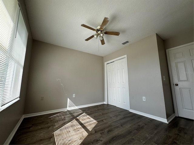 unfurnished bedroom featuring a textured ceiling, dark hardwood / wood-style floors, ceiling fan, and a closet