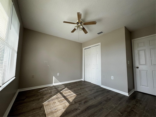 unfurnished bedroom featuring a textured ceiling, dark hardwood / wood-style flooring, ceiling fan, and a closet