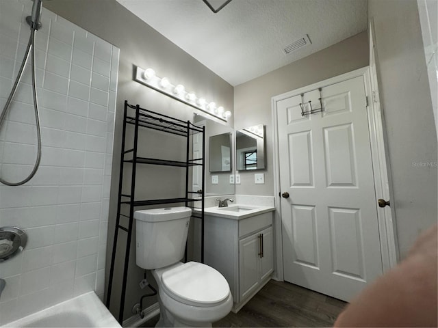 bathroom with hardwood / wood-style flooring, a textured ceiling, vanity, a shower, and toilet