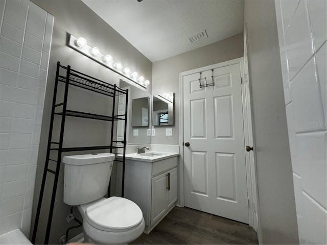 bathroom with toilet, vanity, hardwood / wood-style floors, and a textured ceiling