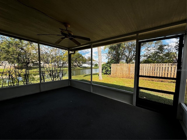 unfurnished sunroom featuring ceiling fan and a water view