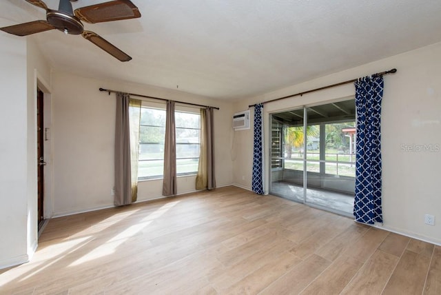 unfurnished room with an AC wall unit, ceiling fan, a healthy amount of sunlight, and light hardwood / wood-style flooring