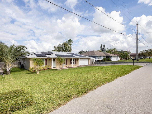 single story home featuring solar panels, a front lawn, and a garage