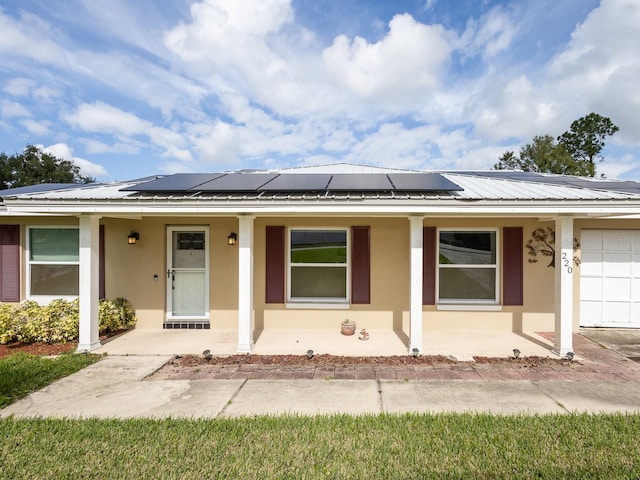 view of front facade with a garage, solar panels, and a porch