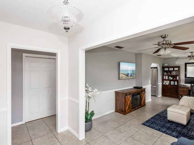 living room with ceiling fan with notable chandelier and light tile patterned floors