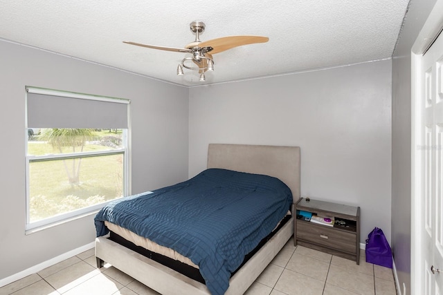 tiled bedroom with ceiling fan and a textured ceiling