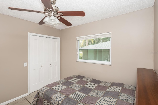 bedroom with light tile patterned floors, ceiling fan, a textured ceiling, and a closet