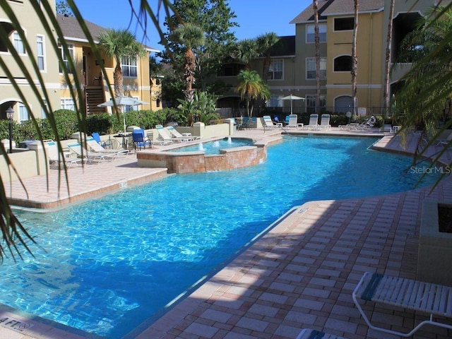 view of swimming pool featuring pool water feature, a patio area, and a community hot tub