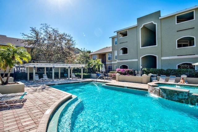 view of swimming pool featuring a patio, a pergola, pool water feature, and a hot tub