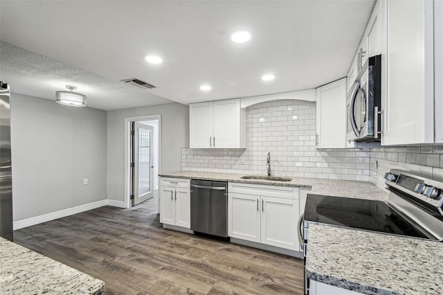 kitchen featuring stainless steel appliances, light stone countertops, sink, white cabinets, and dark wood-type flooring