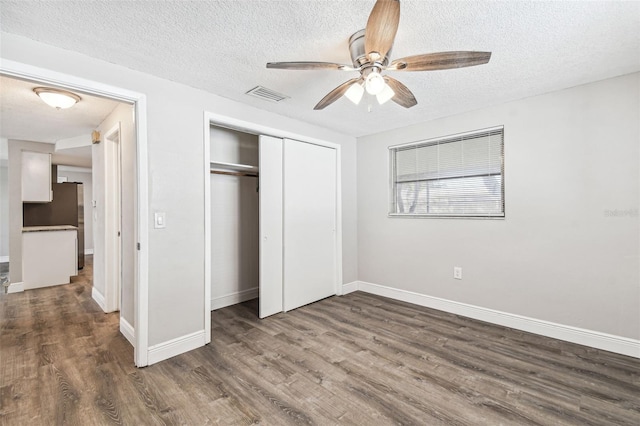 unfurnished bedroom featuring dark wood-type flooring, a closet, a textured ceiling, and ceiling fan