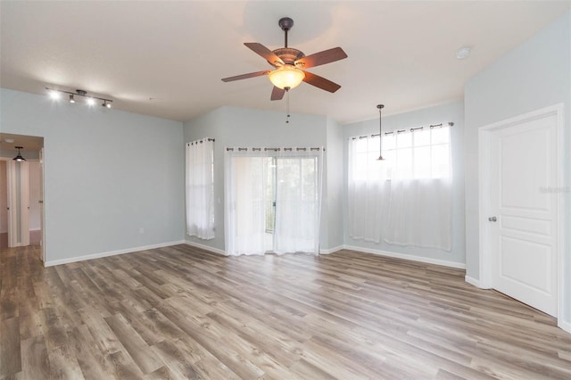 unfurnished room with track lighting, ceiling fan, and light hardwood / wood-style flooring