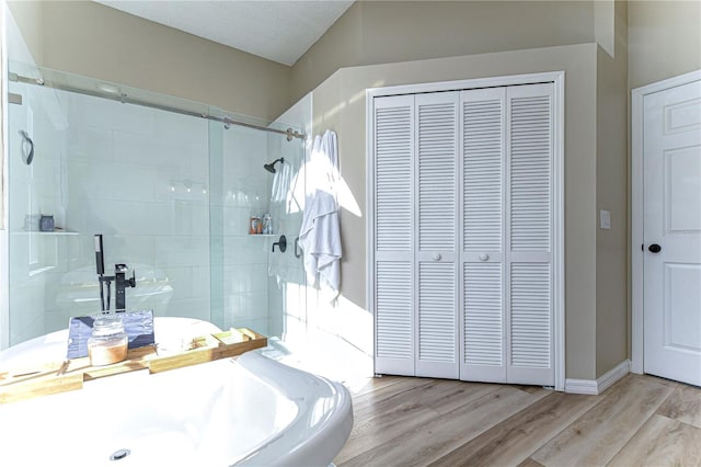 bathroom with hardwood / wood-style floors and a shower with shower door