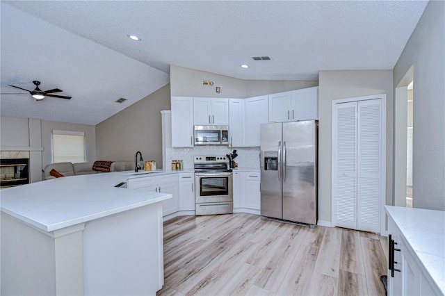 kitchen featuring stainless steel appliances, kitchen peninsula, lofted ceiling, and light hardwood / wood-style flooring