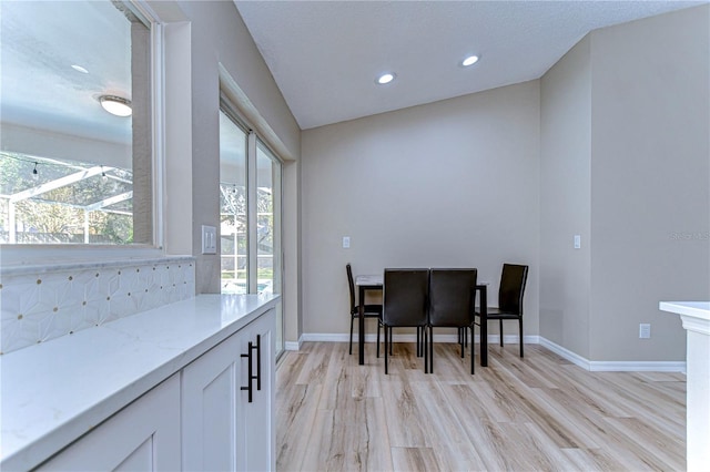 dining space with light hardwood / wood-style floors and vaulted ceiling