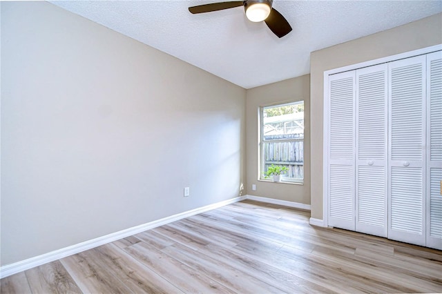 unfurnished bedroom with ceiling fan, a textured ceiling, a closet, and light hardwood / wood-style flooring