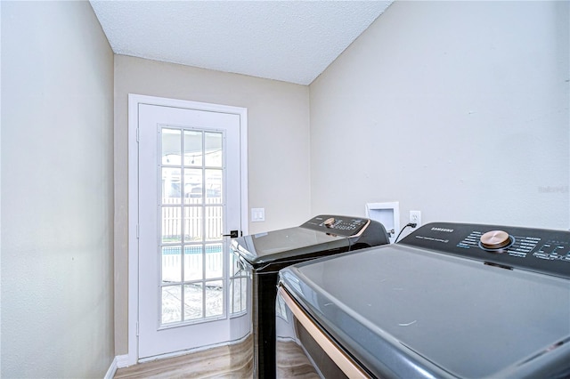 laundry room with a textured ceiling, light wood-type flooring, and washer and clothes dryer