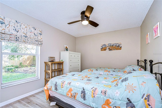 bedroom with a textured ceiling, light hardwood / wood-style flooring, and ceiling fan