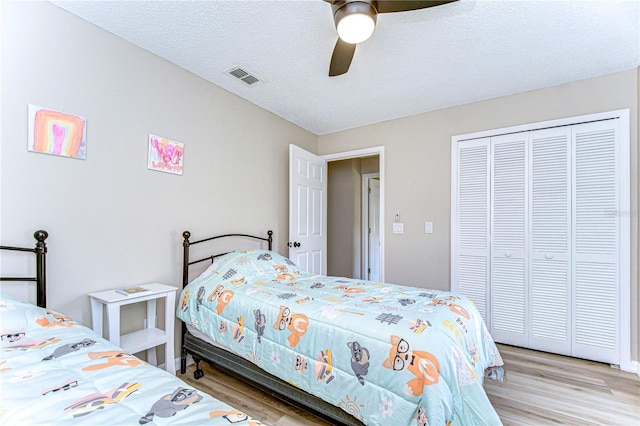 bedroom featuring a textured ceiling, light hardwood / wood-style floors, ceiling fan, and a closet