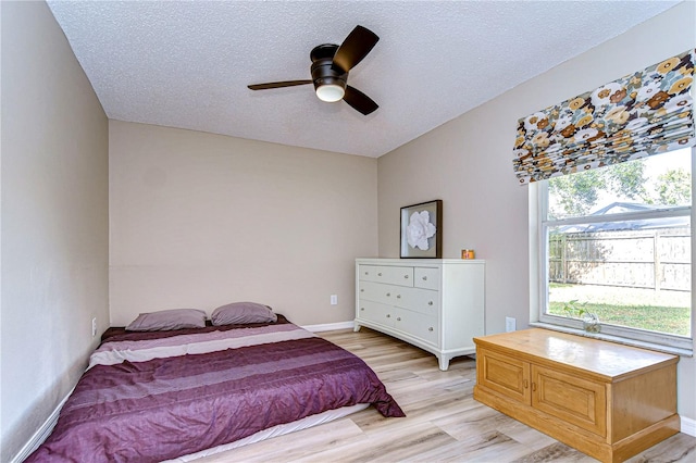 bedroom with a textured ceiling, ceiling fan, and light hardwood / wood-style flooring