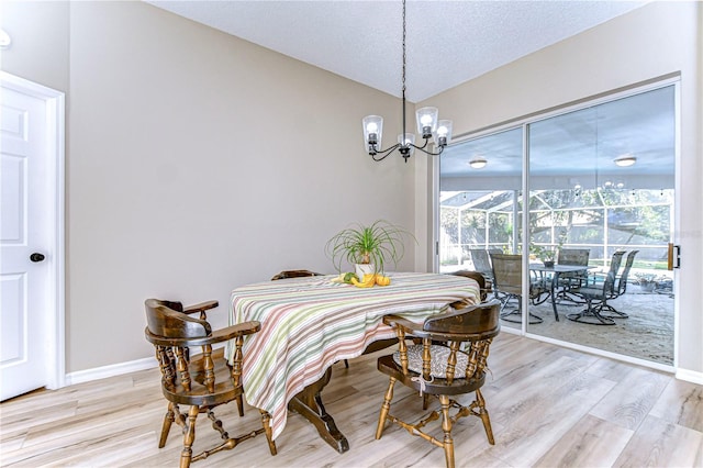 dining space featuring a chandelier, a textured ceiling, and light wood-type flooring