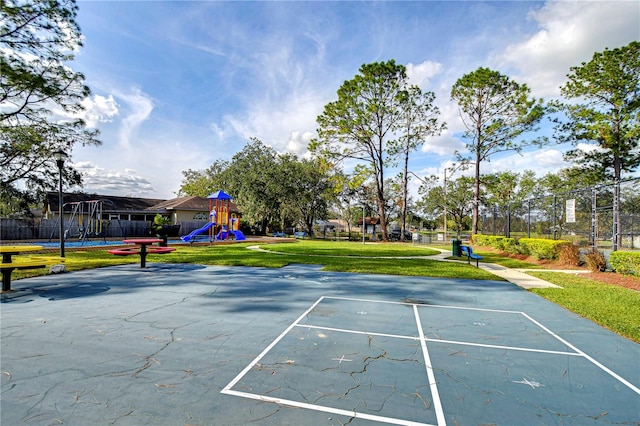 exterior space with a playground, a lawn, and basketball hoop