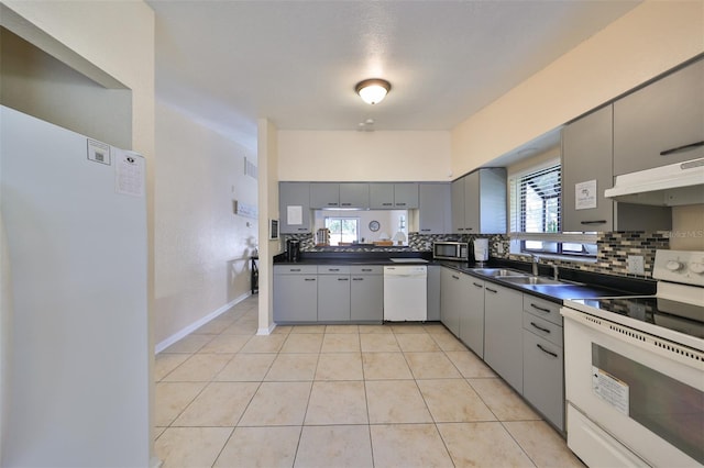 kitchen with sink, tasteful backsplash, gray cabinetry, light tile patterned flooring, and white appliances