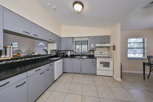 kitchen featuring light tile patterned flooring, sink, white appliances, gray cabinets, and vaulted ceiling